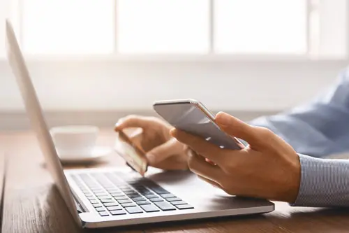 A person holding their phone and credit card while buying something online