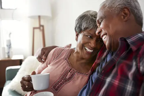 Elderly couple sitting with one another drinking coffee